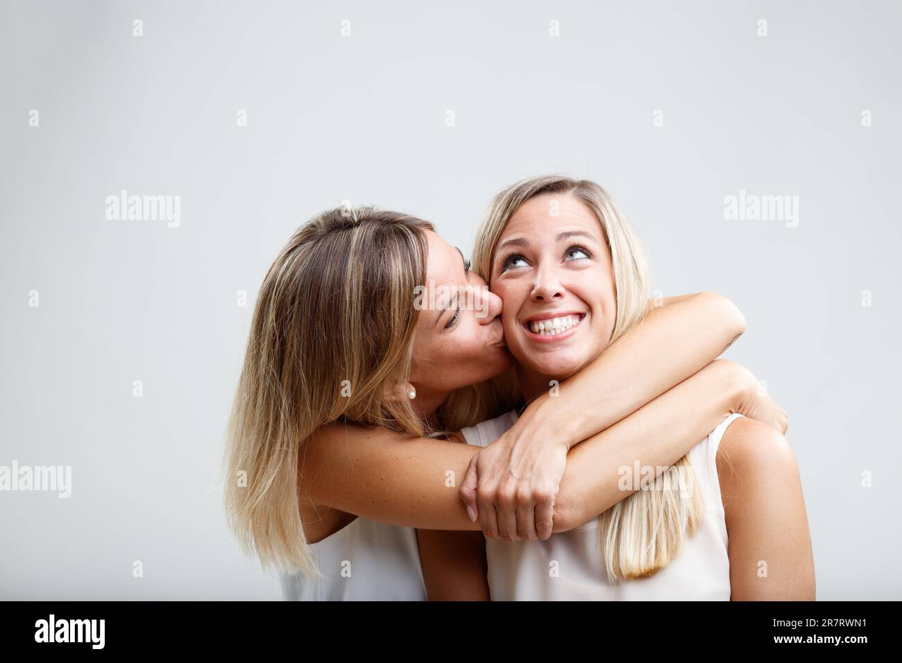 Deux femmes blondes échangent des embrasses affectueuses, des caresses et des baisers de joue. Leur lien reflète la sisterhood, comme ils se posent ensemble affectueusement Banque D'Images