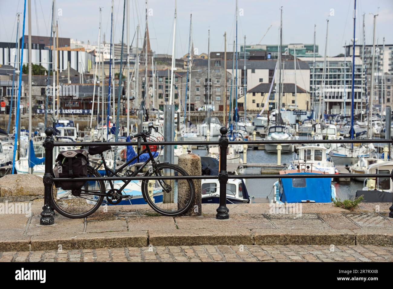 Une seule bicyclette noire repose sur les rampes de la jetée pavée West Pier sur le Barbican de Plymouth. Dans la mise au point douce au-delà du bassin intérieur avec des yachts a Banque D'Images