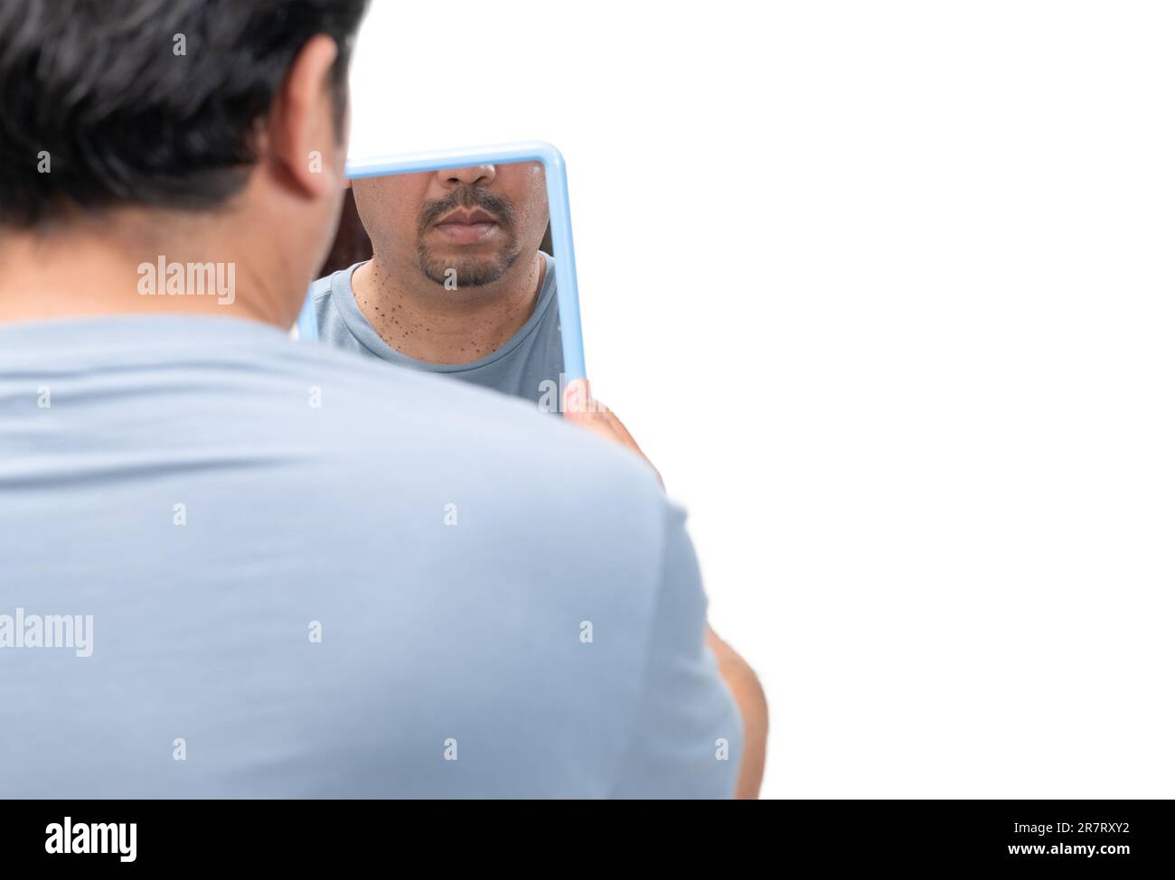 Homme barbu regardant dans le miroir pour des marques de peau ou acrochordon sur son cou isolé sur fond blanc. Concept de soins de santé Banque D'Images