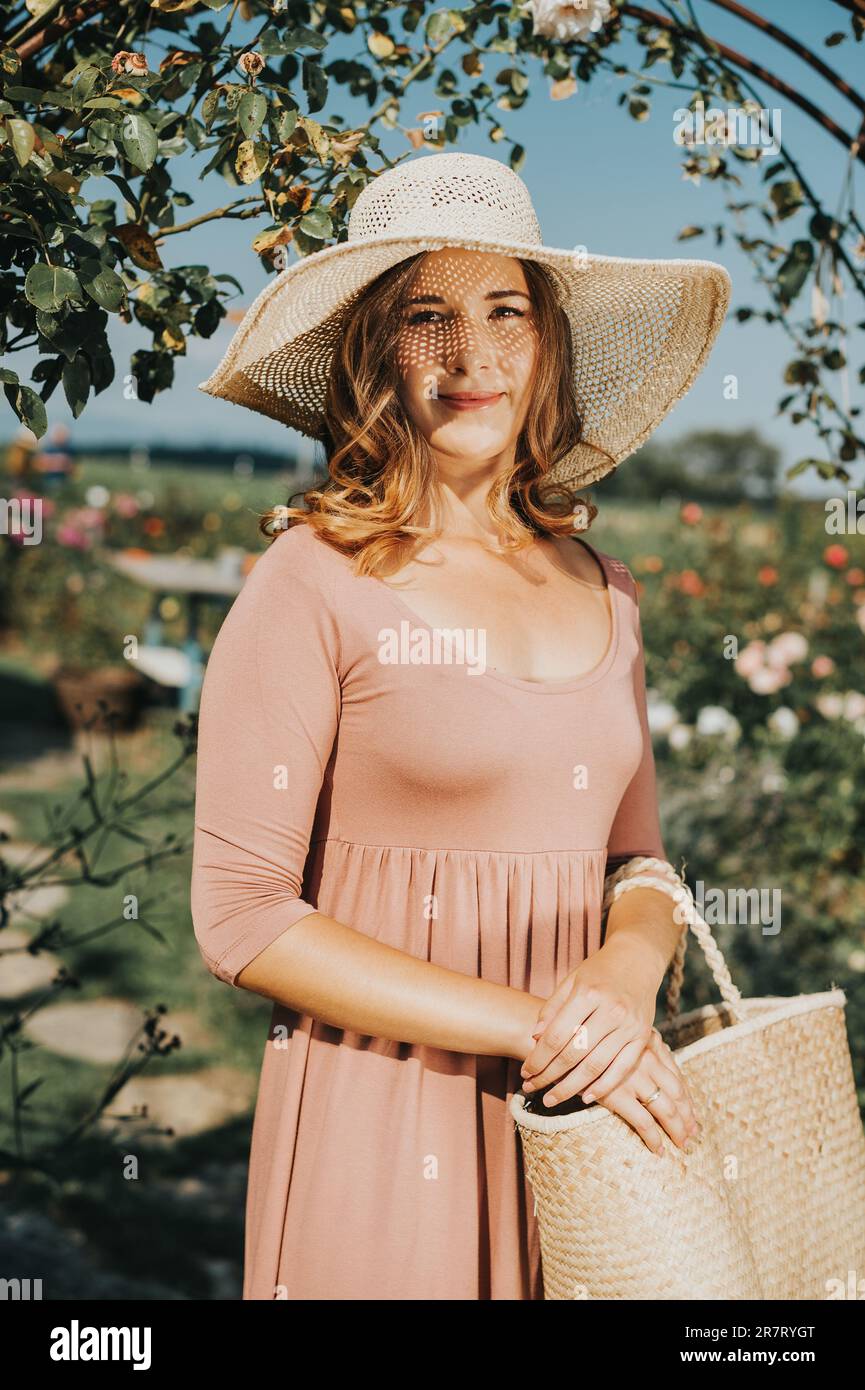 Portrait extérieur de jeune belle fille de 18 ans dans le jardin d'automne, portant un chapeau, tenant sac de paille Banque D'Images
