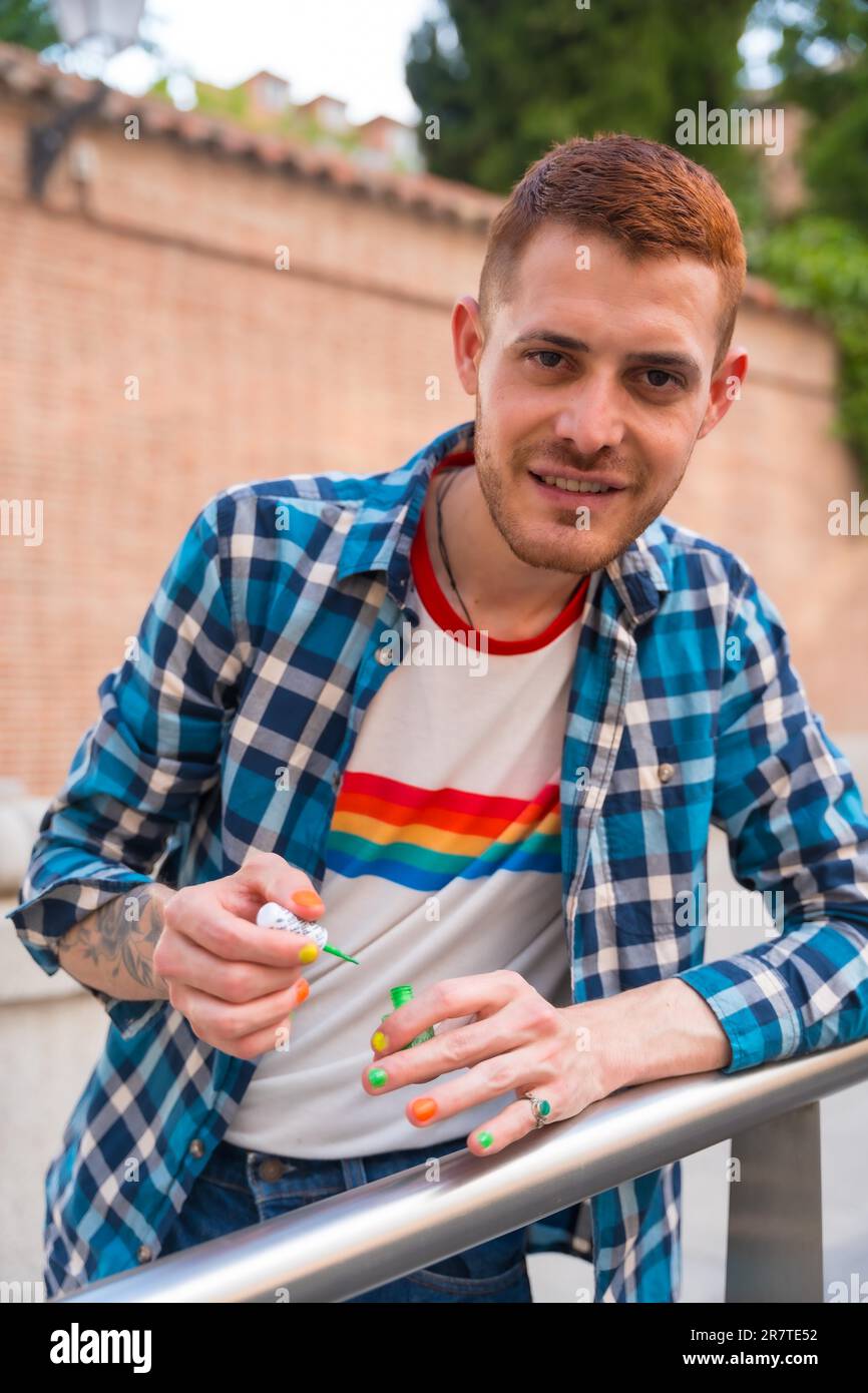 Beau gay homme pachant ses ongles maquillage avec le drapeau lgbt arc-en-ciel dans la ville, fête de fierté et homosexuel Banque D'Images