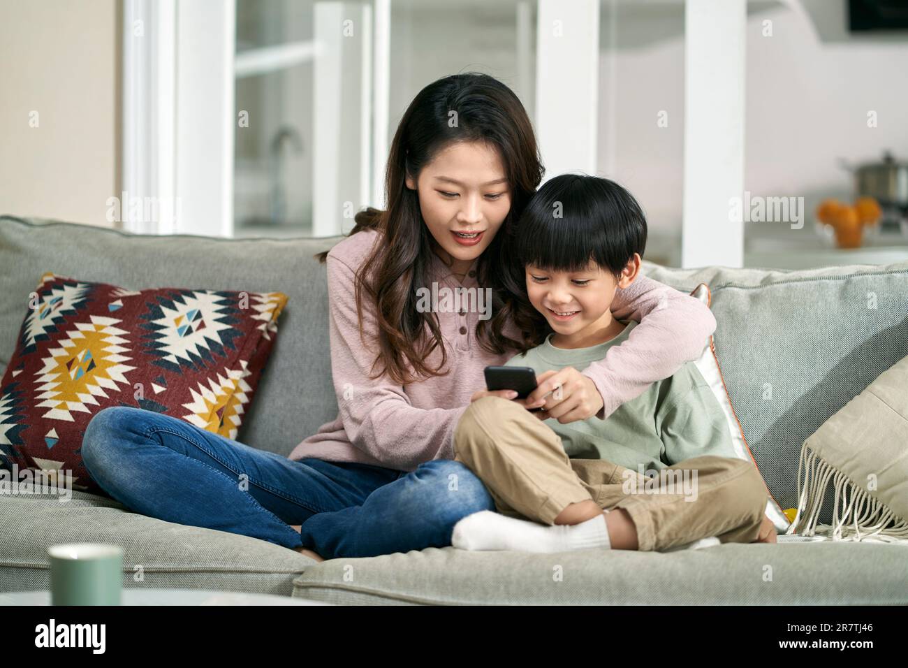 mère et fils asiatiques heureux assis sur un canapé de famille regardant les photos de téléphone portable ensemble Banque D'Images