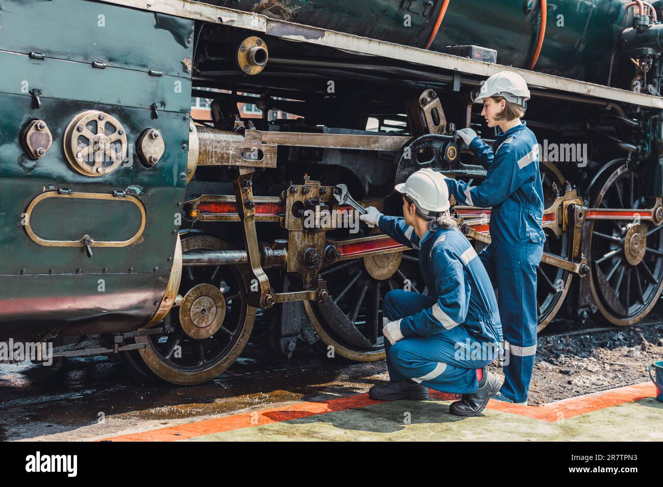 Équipe de mécanicien de train travaillant entretien entretien vieux sale vieux moteur à vapeur classique dans l'atelier de réparation de train à la gare. Banque D'Images