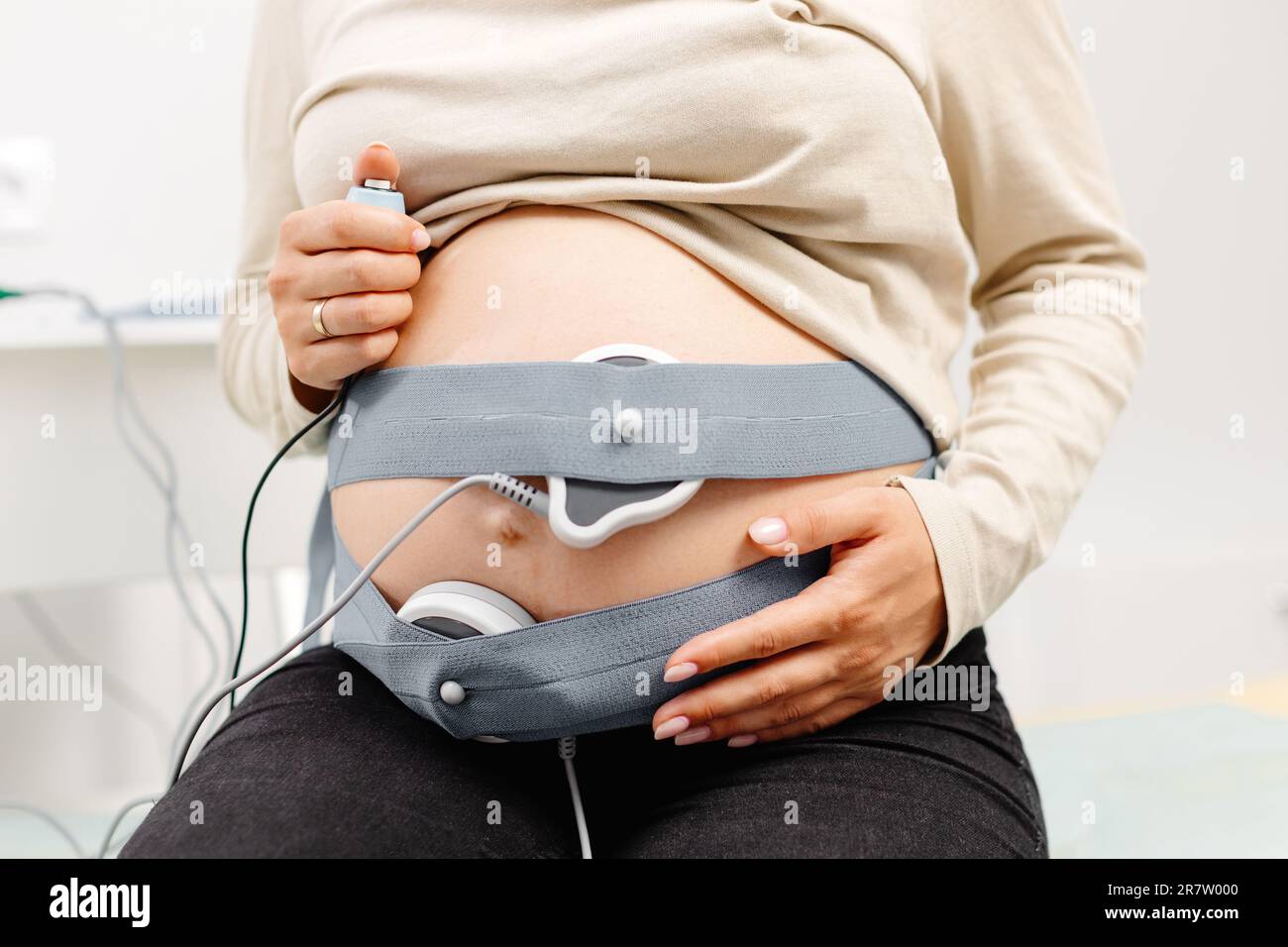 Femme enceinte vérifiant le rythme cardiaque fœtal par surveillance fœtale. Mère enceinte avec sage-femme qui ajuste les capteurs hors cardiotocographie (CTG). Banque D'Images