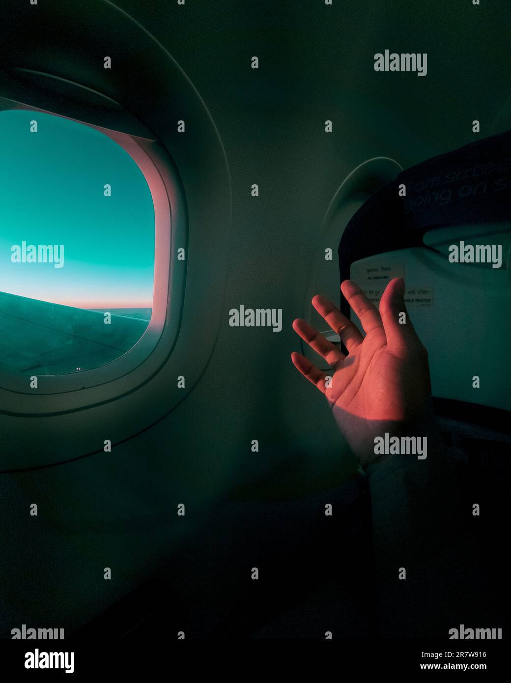 Une main humaine s'étire d'une fenêtre d'avion Banque D'Images