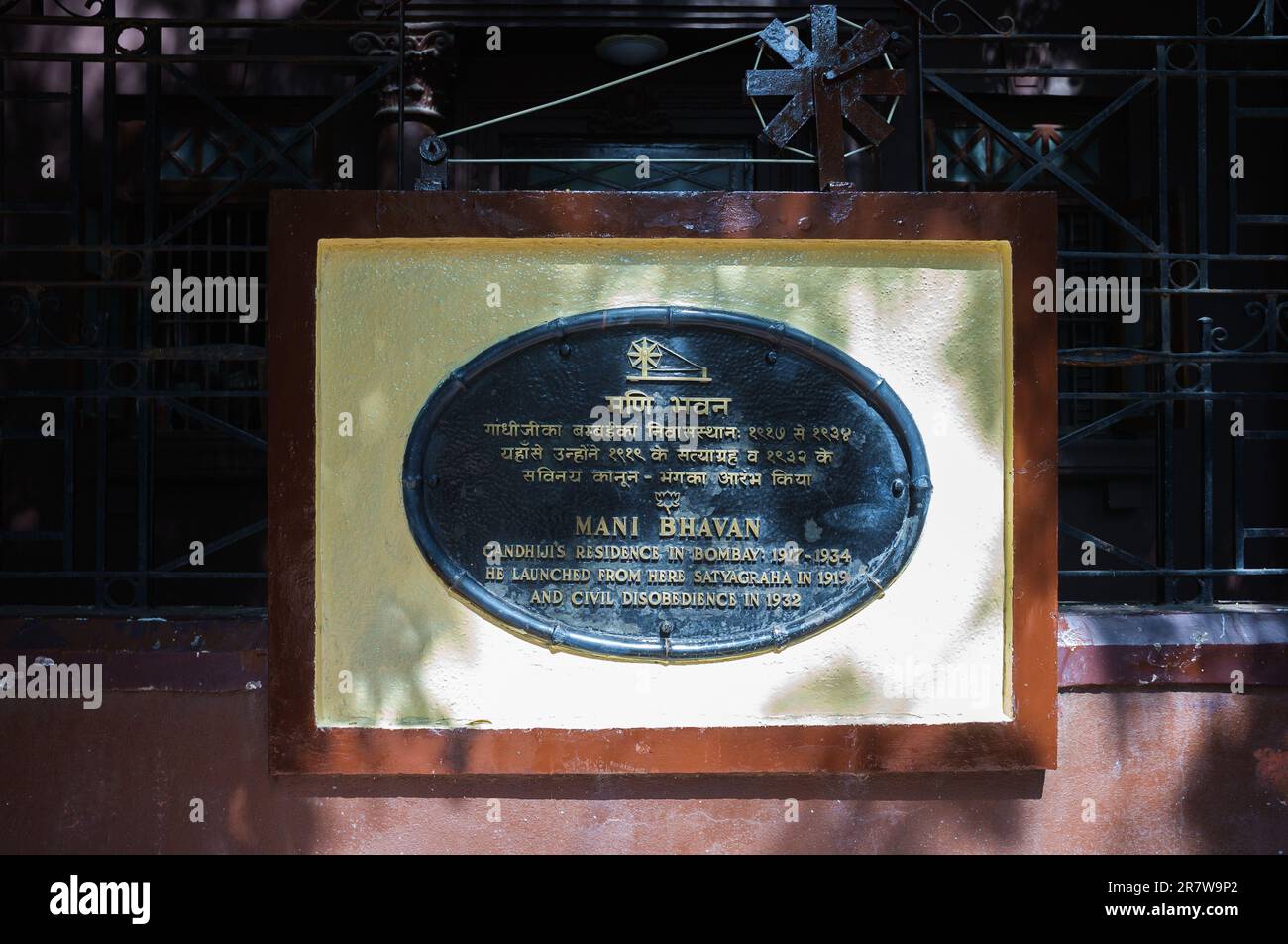 Une plaque rectangulaire verticale avec du texte inscrit en caractères noirs est apposée sur le côté d'un bâtiment Banque D'Images