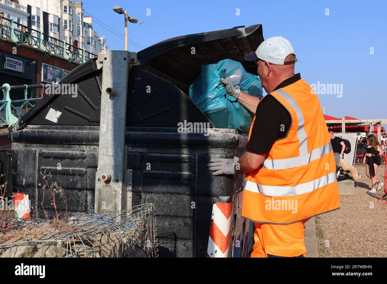 Dans une veste haute visibilité, un aspirateur place un sac de déchets dans une poubelle Banque D'Images