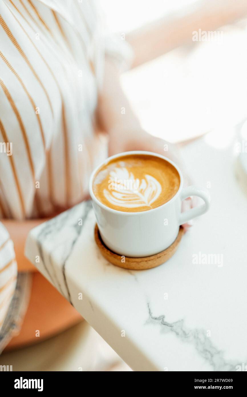 Femme tenant une tasse de café à la main dans un café-restaurant. Banque D'Images