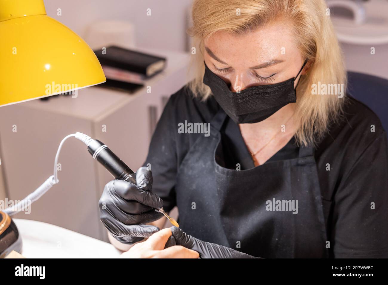 Le technicien se concentre sur les ongles du client sous un éclairage supplémentaire Banque D'Images