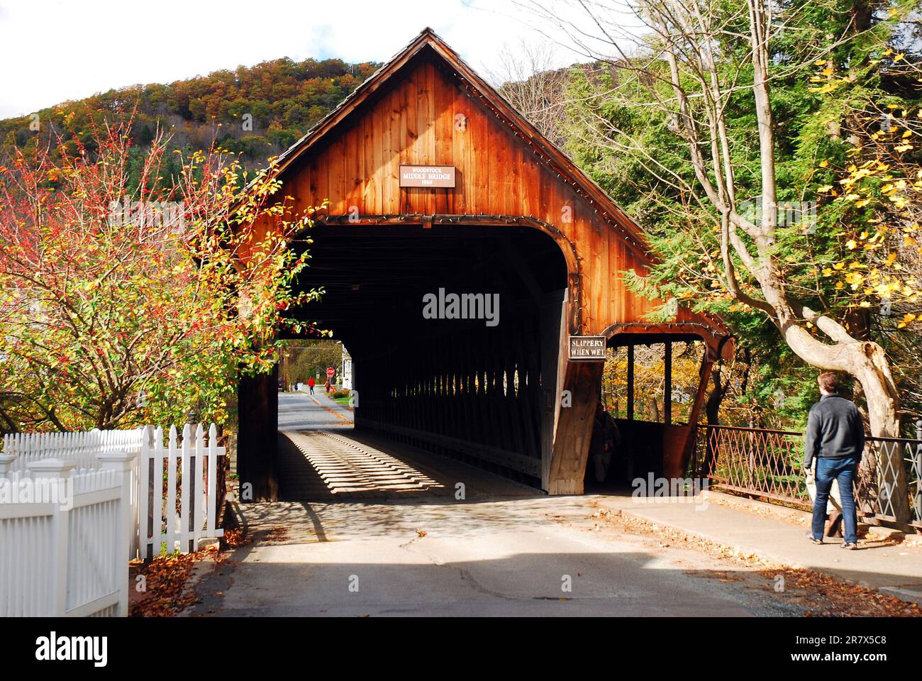Un jeune homme marche vers un pont couvert dans une petite ville du Vermont, le jour d'automne ensoleillé Banque D'Images