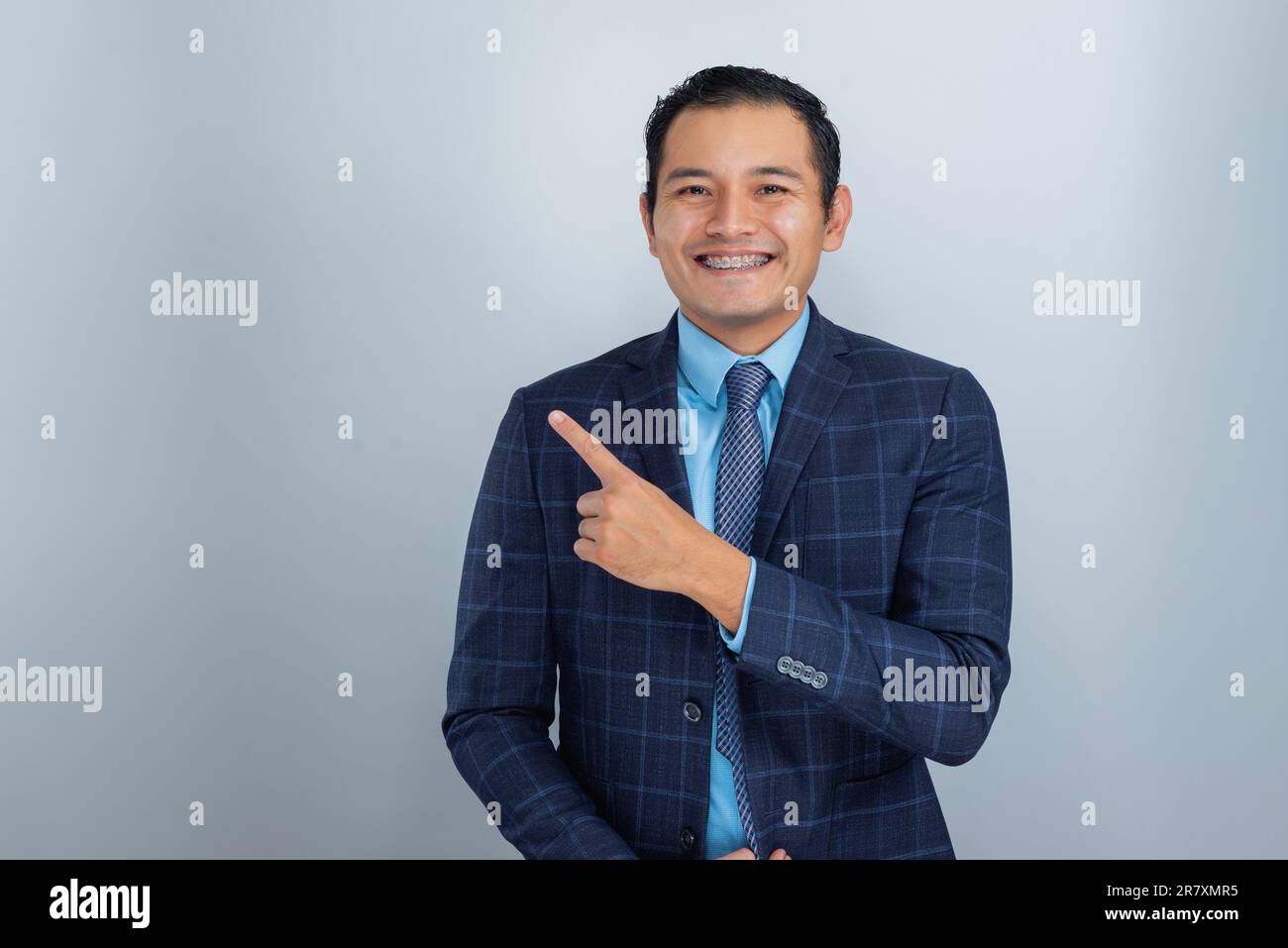 Jeune mexicain à la peau brune habillé comme un entrepreneur ou un homme d'affaires pointe heureusement avec le doigt, une personne Banque D'Images
