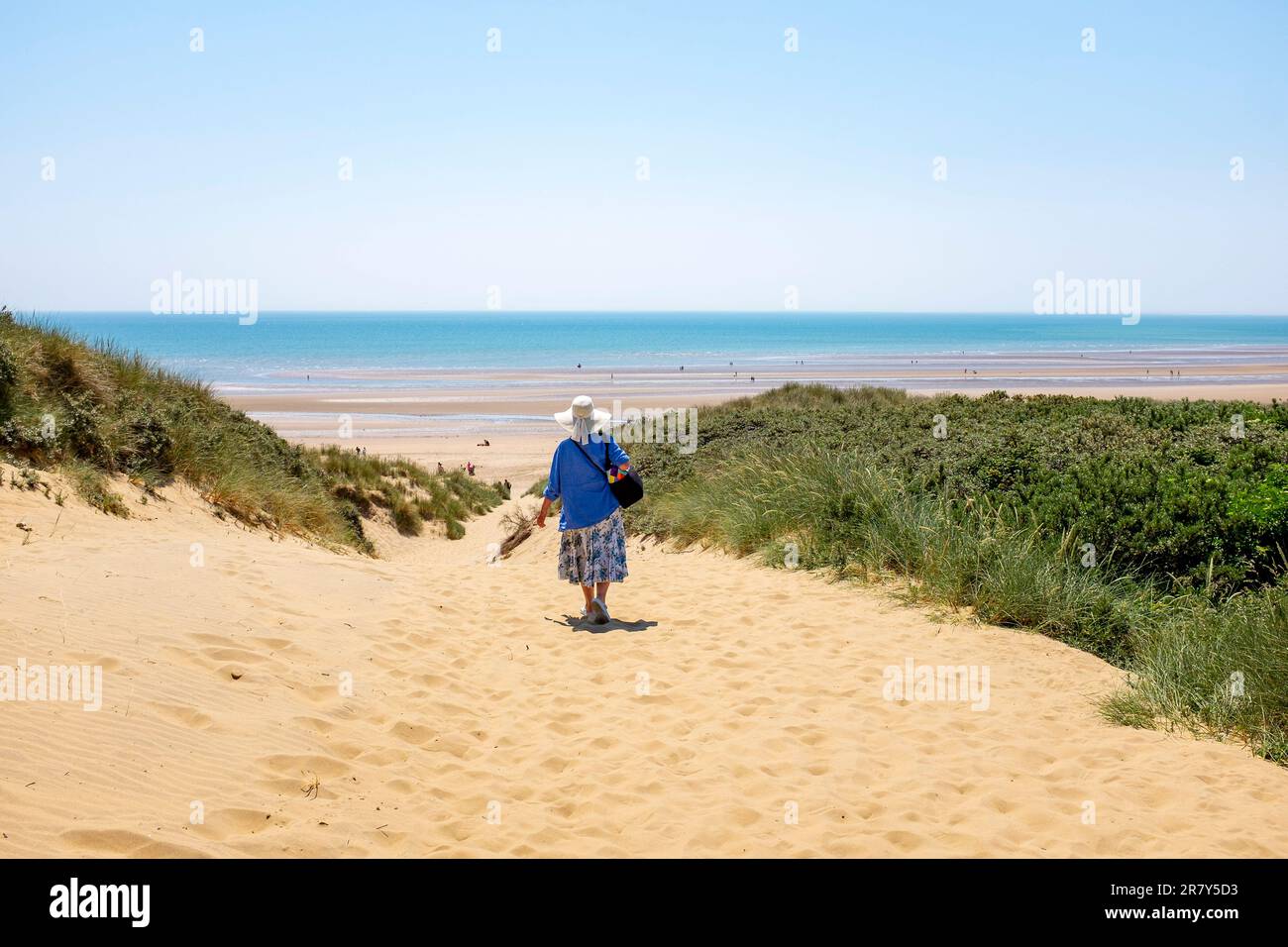 Camber Sands Beach East Sussex , Angleterre , Royaume-Uni - une femme marchant à travers les dunes de sable sur la plage lors d'une belle journée chaude et ensoleillée en été Banque D'Images