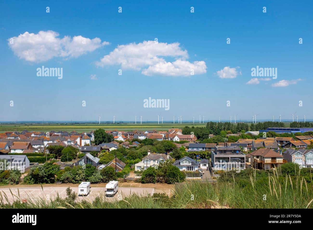 Camber Sands Beach East Sussex , Angleterre , Royaume-Uni - vue sur les maisons de Camber et le parc éolien au loin Banque D'Images