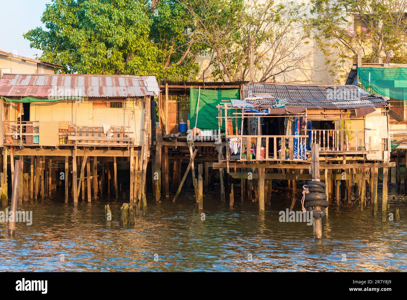 Maisons à pilotis le long de la rivière Chao Phraya dans la mégalopole de Bangkok. Dans de nombreuses parties, les maisons simples ont été démolies et sont remplacées de Banque D'Images