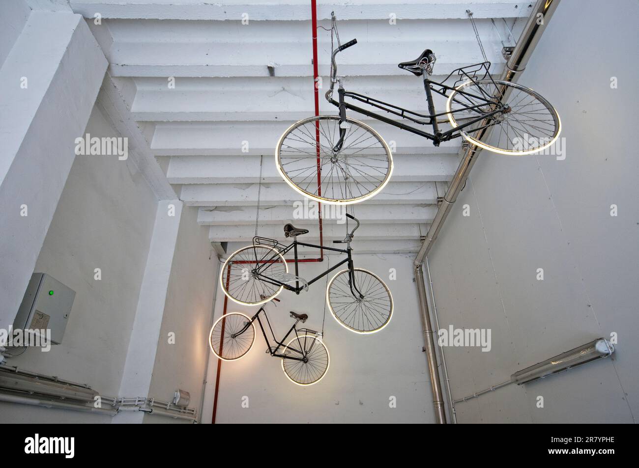 Vélos suspendus avec pneus lumineux dans un garage de location de vélos, Bruges, Flandre, Belgique Banque D'Images