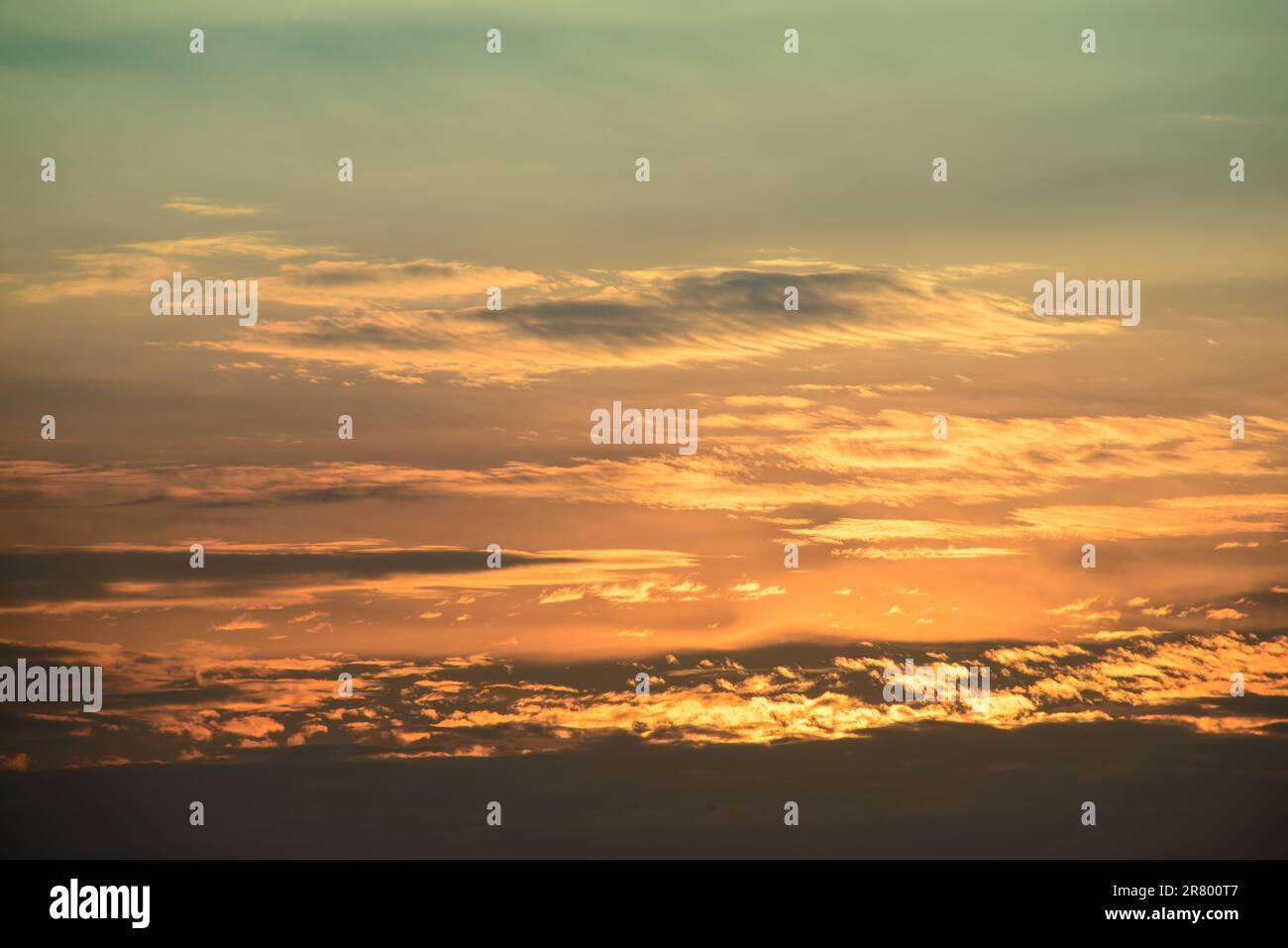Rangée après rangée de nuages blancs soigneusement disposés. Magnifique ciel orange-jaune au crépuscule. Banque D'Images