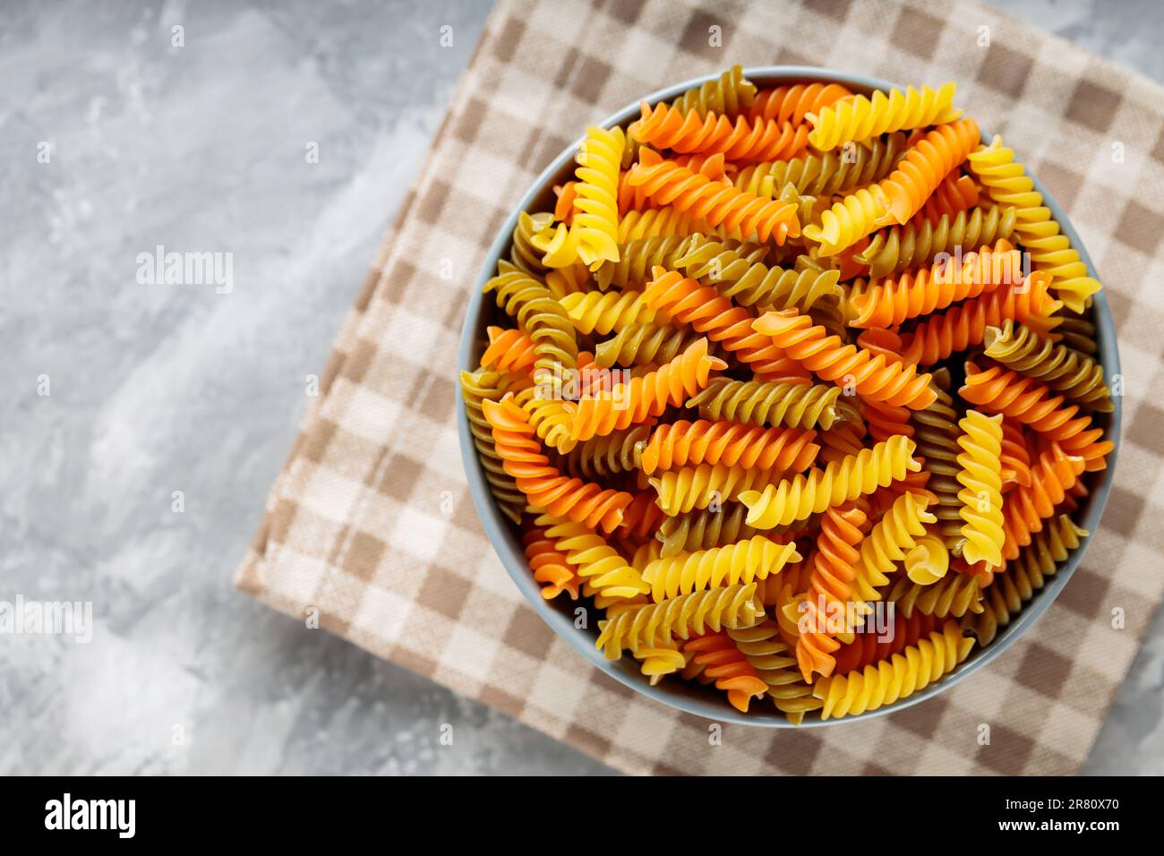 Pâtes fusilli crues sur béton. Pâtes rotini ou fusilli de trois couleurs sur une serviette en lin. Cuisine italienne Banque D'Images