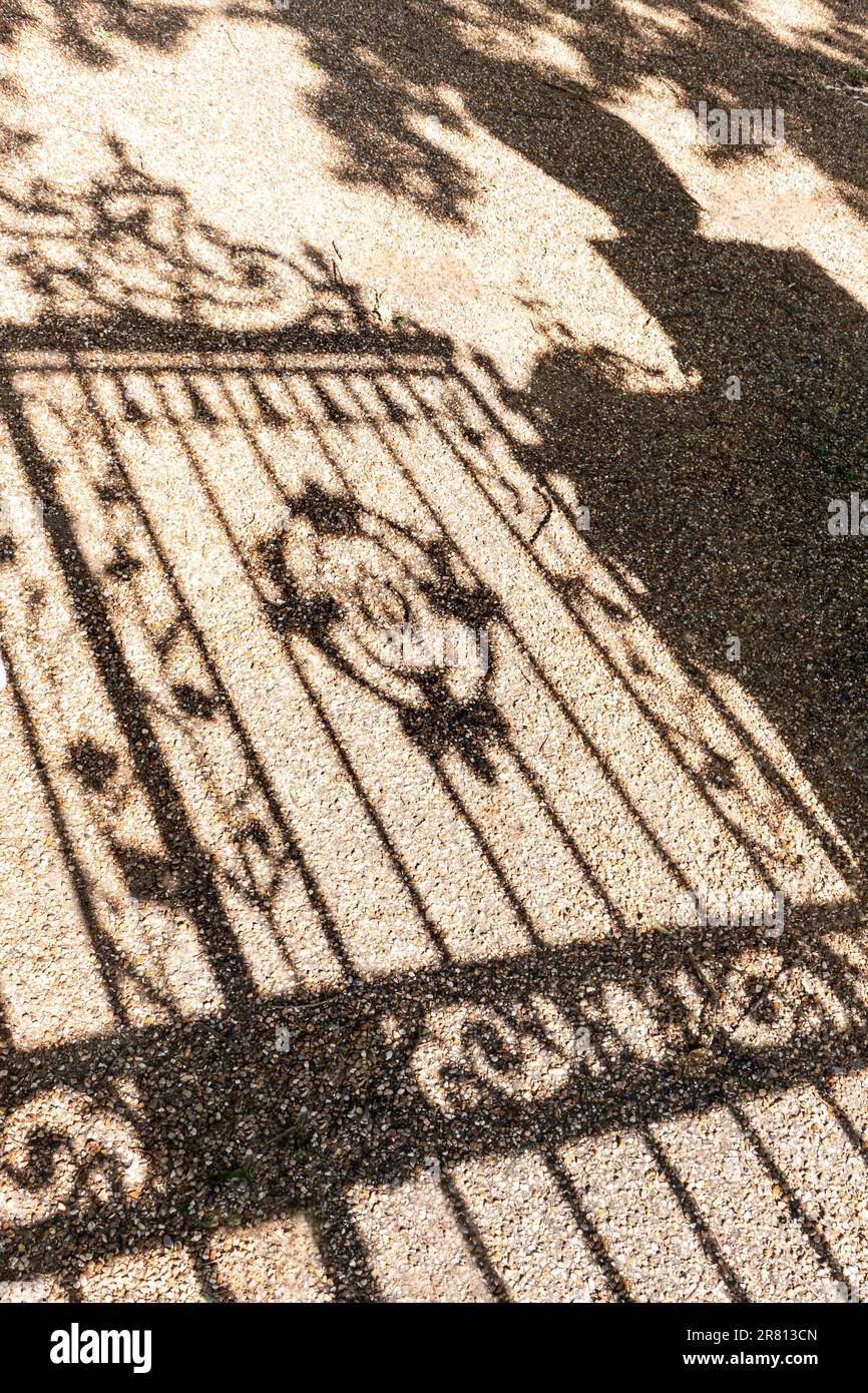PORTES D'ENTRÉE PRINCIPALE Silhouette des portes en fer forgé de la maison majestueuse projetées sur le chemin d'entrée en pierre de gravier Surrey Royaume-Uni Banque D'Images