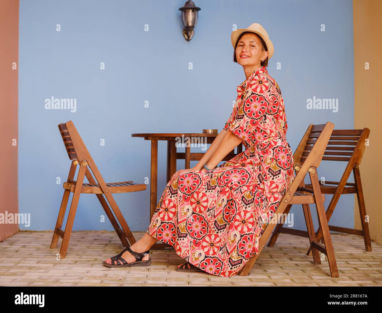 Voyage d'été à l'île de Rhodes, Grèce. Une jeune femme asiatique vêtue  d'une robe rouge ethnique se promène dans les rues colorées de la ville de  Rhodes. Tourisme, vacances, voyage en solo