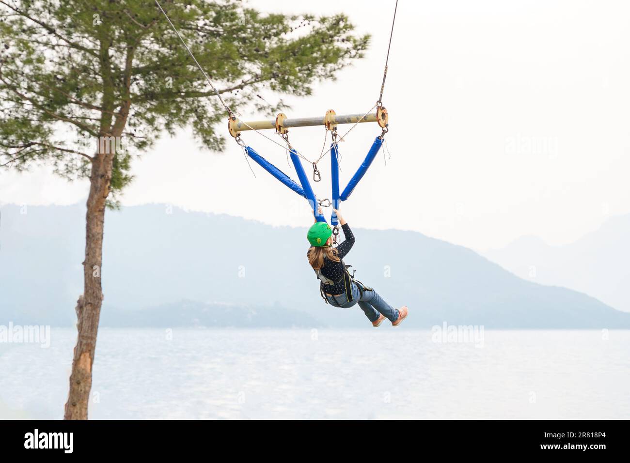 Une adolescente à l'adolescence, un sandow volant dans le parc d'attractions de corde. Équipement de harnais d'escalade, casque de sécurité sport vert. Course d'obstacle suspendu. Enfants enfants Banque D'Images