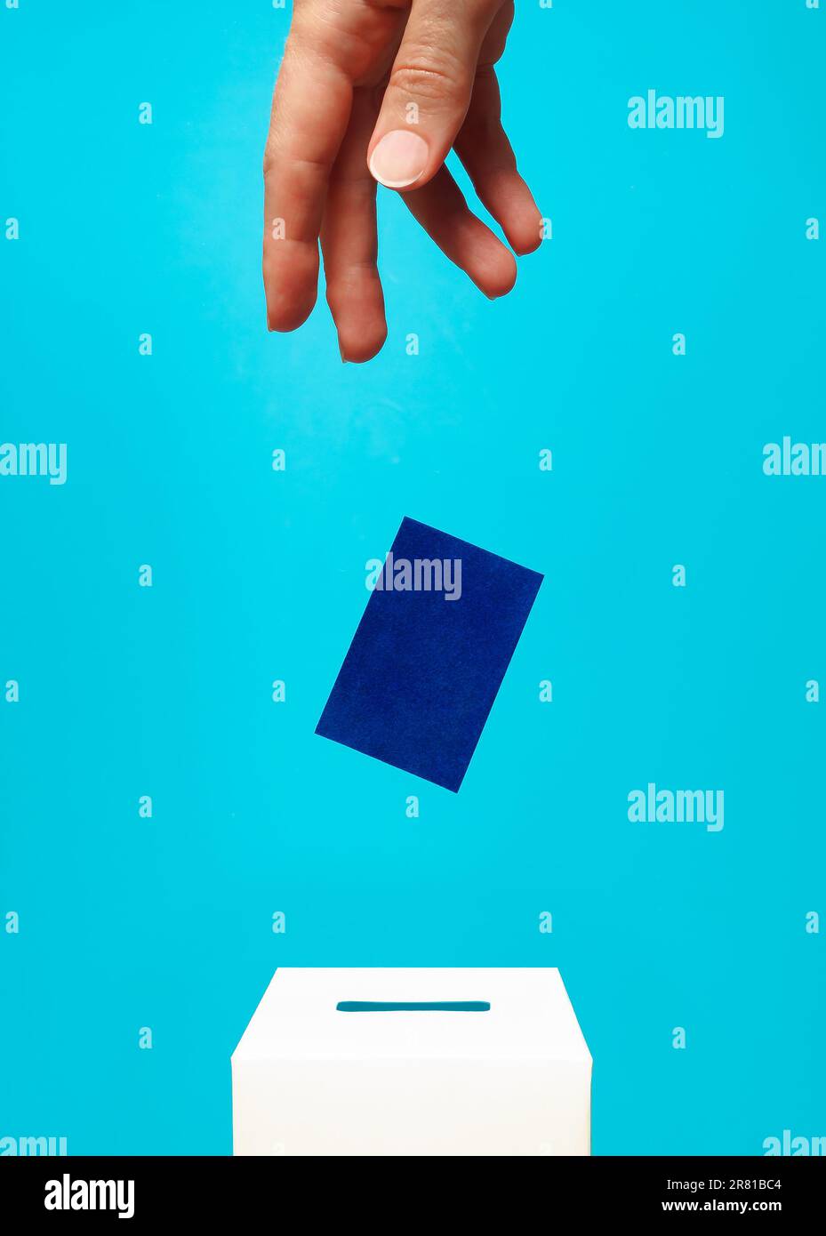 concept d'élection - la main d'une femme met une carte bleue dans une boîte de vote blanche avec une fente, le fond est bleu, la lévitation Banque D'Images