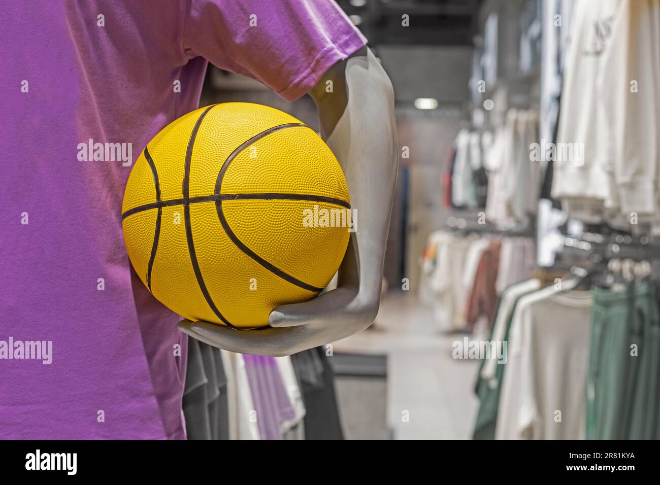 basket-ball jaune dans les mains d'un mannequin dans une boutique de sport Banque D'Images