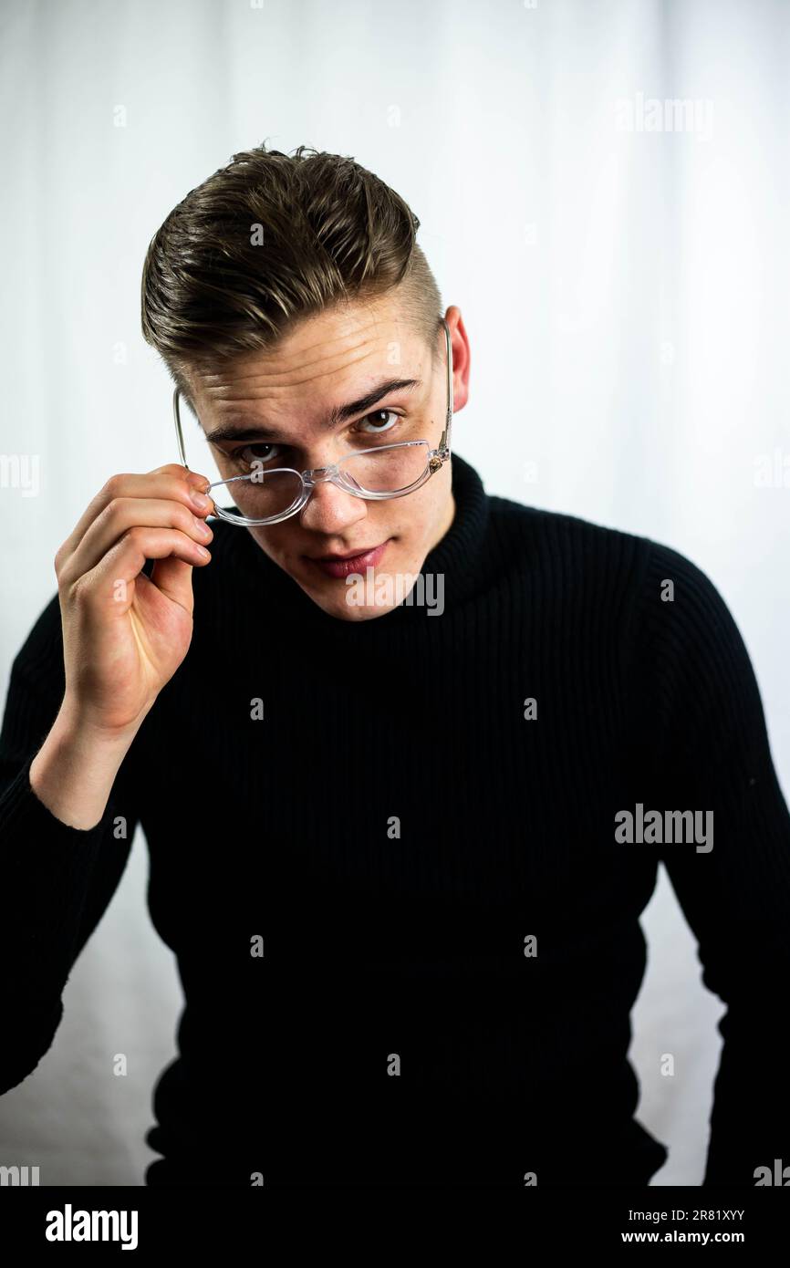 Un homme mûr portant une chemise noire, des lunettes, et regardant vers le haut avec une expression de contemplation Banque D'Images