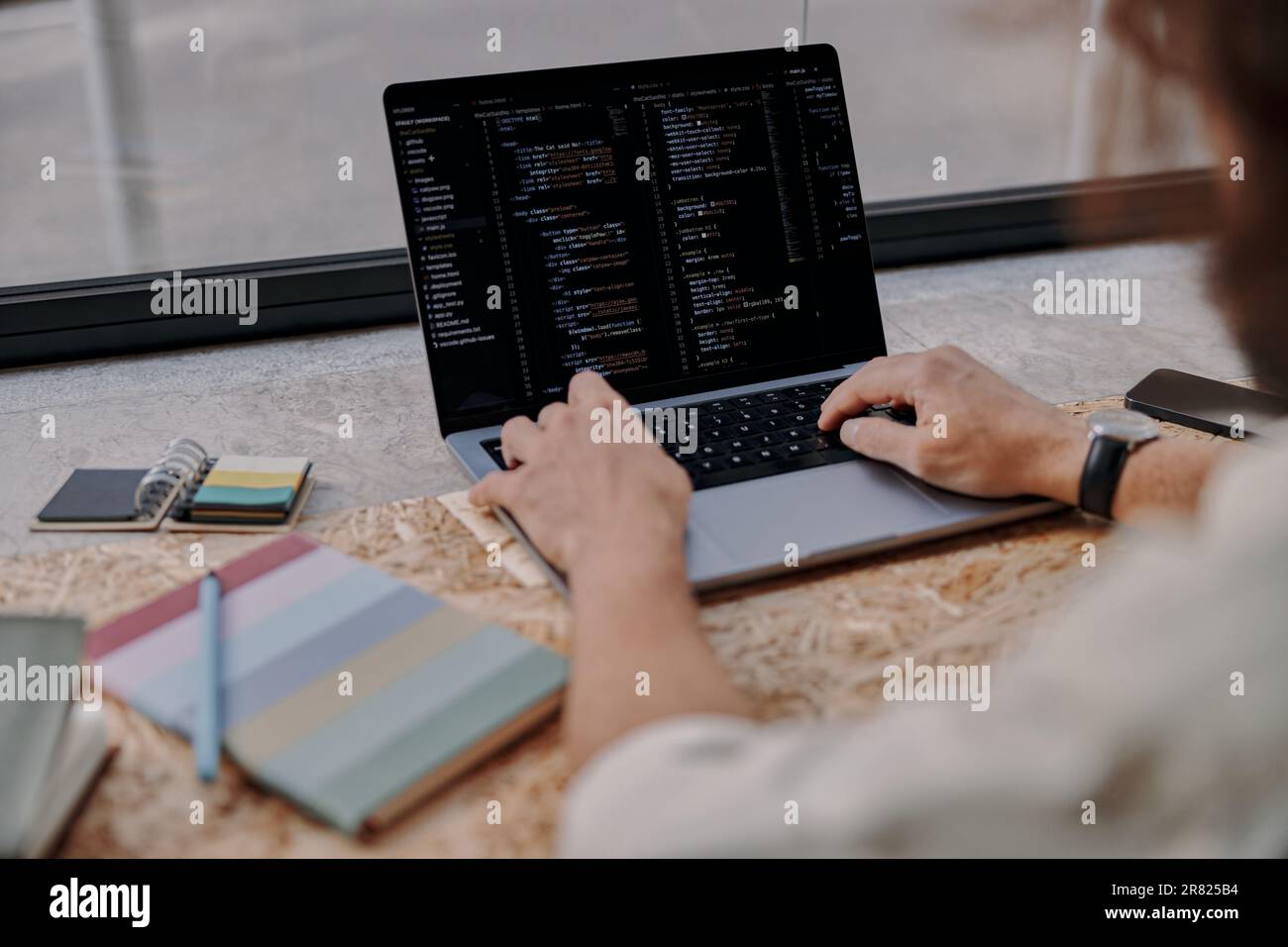 Gros plan des mains de programmer hommes écrire le code sur l'ordinateur portable assis dans le café près de la fenêtre Banque D'Images