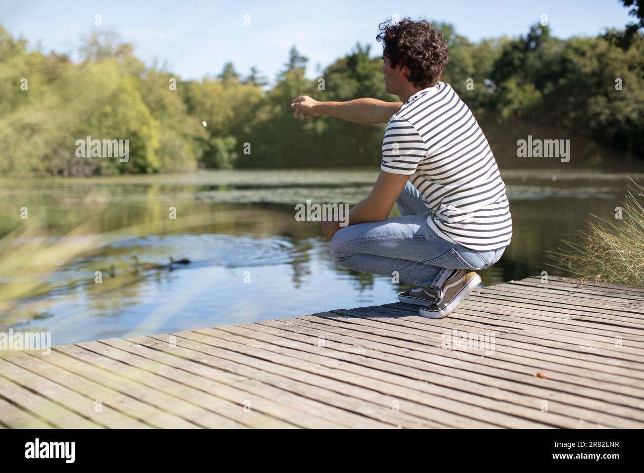 homme jetant la pierre dans un lac Banque D'Images