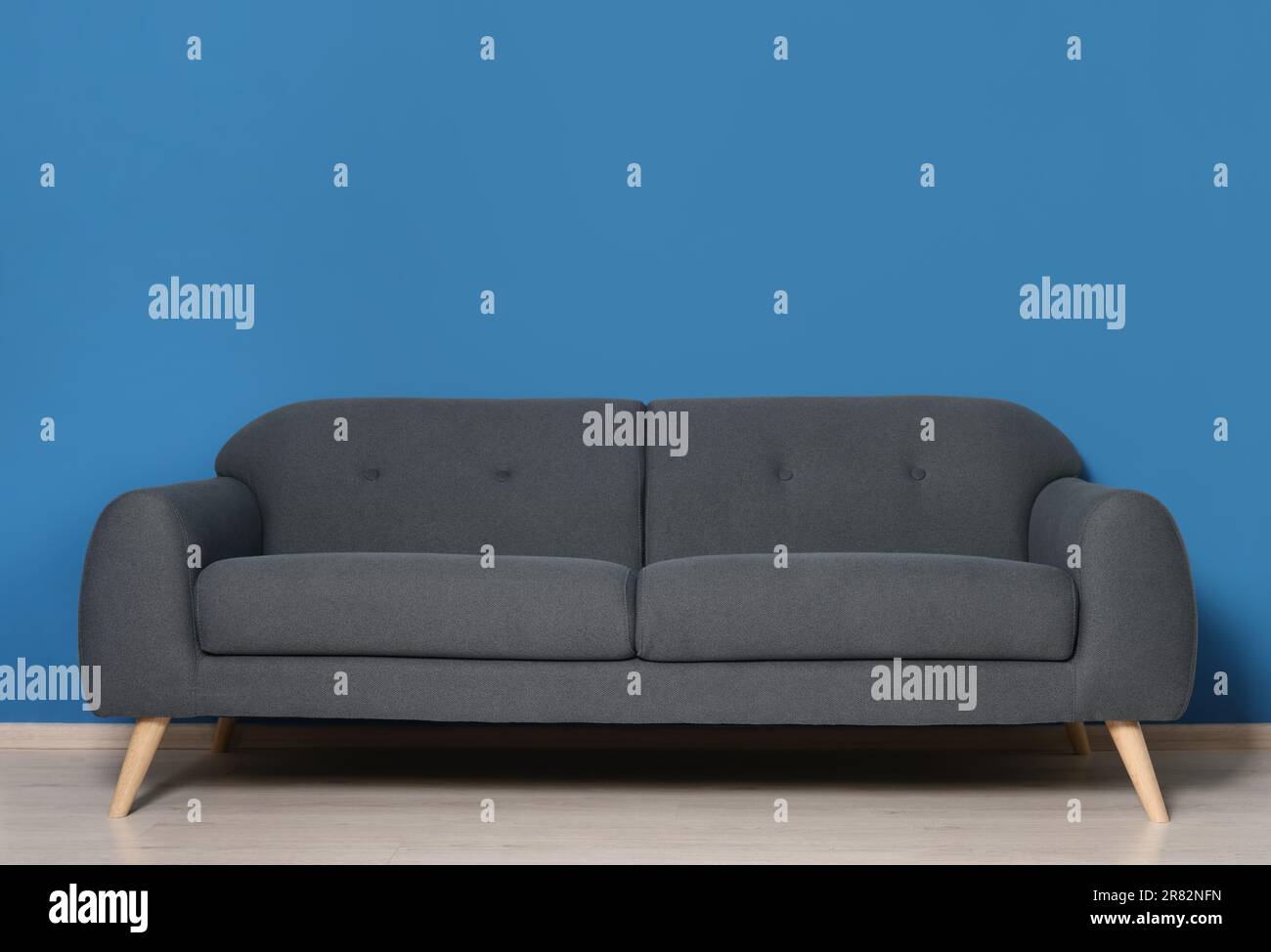 Élégant canapé gris près du mur bleu dans la chambre. Design intérieur Banque D'Images