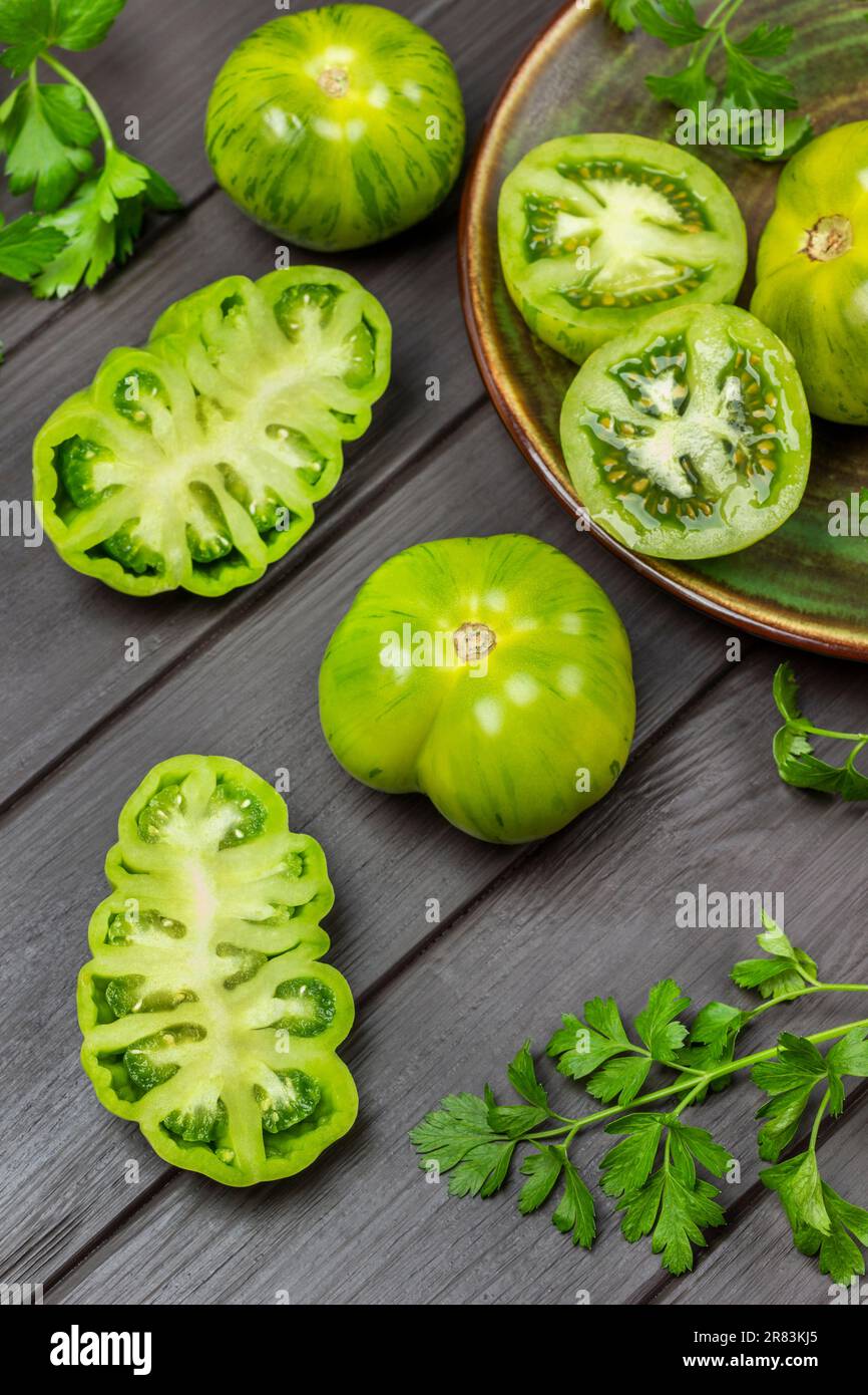 Tomates vertes entières et hachées sur la table. Pose à plat. Arrière-plan en bois sombre. Banque D'Images