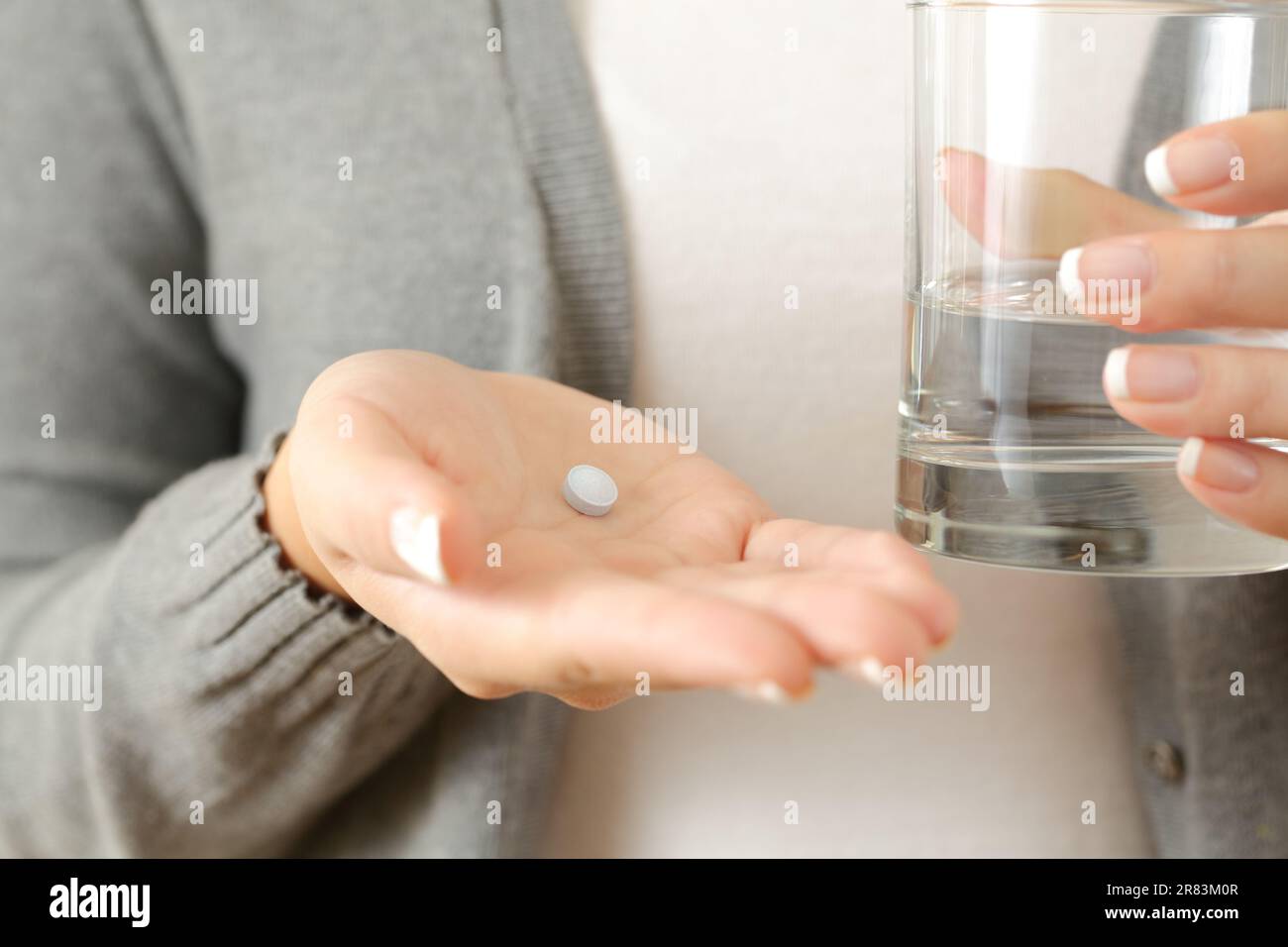 Vue de face gros plan d'une femme mains tenant une pilule et un verre d'eau Banque D'Images