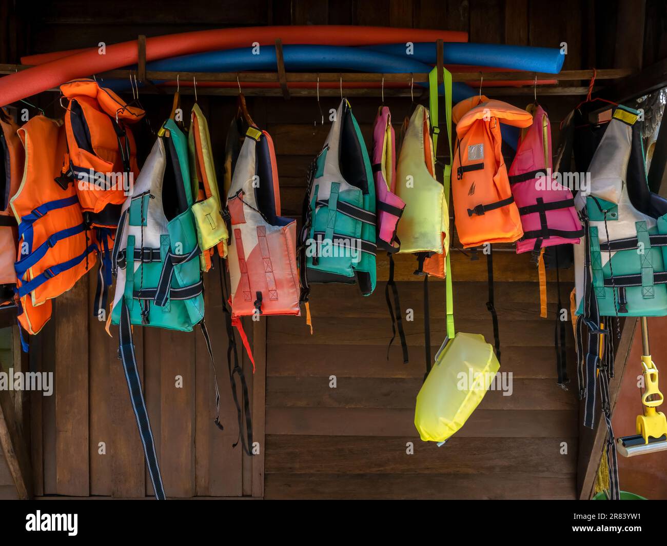 Les gilets de sauvetage multicolores sont suspendus sur un mur en bois pour les clients du complexe qui souhaitent pratiquer des activités nautiques, du kayak, du paddleboard, etc Banque D'Images