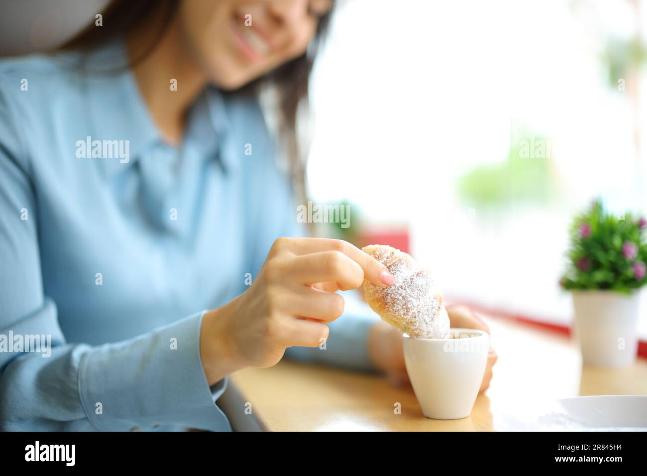 Bonne femme qui a mangé un croissant dans une tasse de café dans un restaurant Banque D'Images