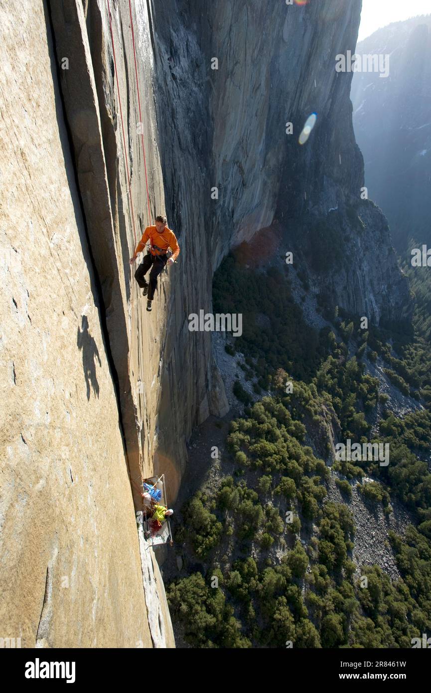 Un homme qui fait une pause dans les terrains d'exécution tandis qu'une femme fait le ventre d'un bord de mer en contrebas sur El Cap dans le parc national de Yosemite, en Californie. Banque D'Images