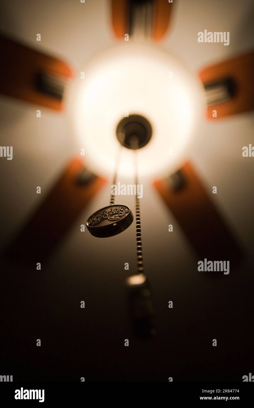 Détail d'un ventilateur de plafond éclairé la nuit dans une pièce sombre. Banque D'Images