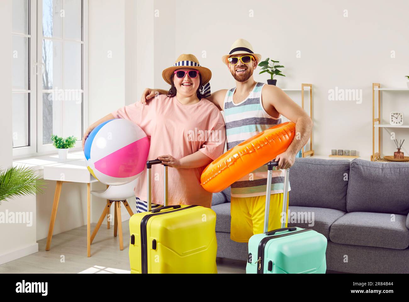 Joyeux couple drôle en vacances d'été avec des valises et ballon gonflable et anneau Banque D'Images