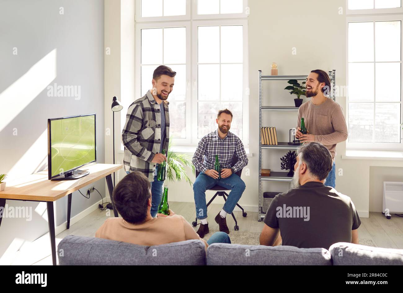 Groupe d'amis à barbe mûrs parlant pendant un match de football à la télévision à la maison avec de la bière. Banque D'Images