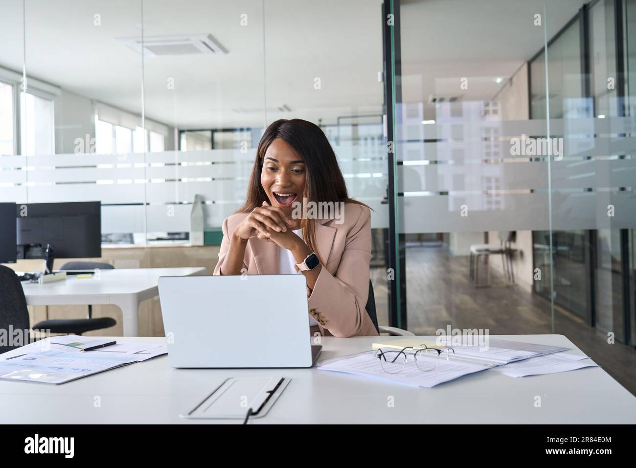 Une femme d'affaires afro-américaine surprend avec enthousiasme un ordinateur portable au bureau. Banque D'Images