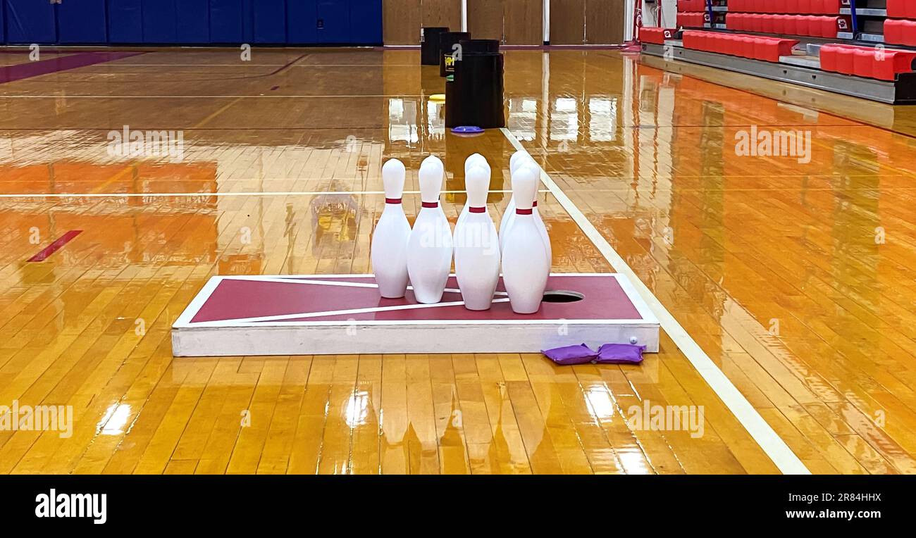 Cornhole, bowling, Frisbee, confiture de caniches, jeux mis en place sur un étage de salle de gym pour les cours de gym de lycée. Banque D'Images