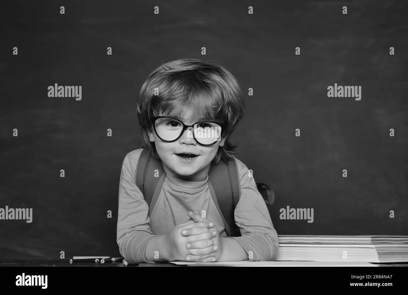 Bonne humeur souriant largement à l'école. Un petit garçon drôle qui pointe sur le tableau noir. Retour à l'école. Concept d'école et d'éducation. Banque D'Images