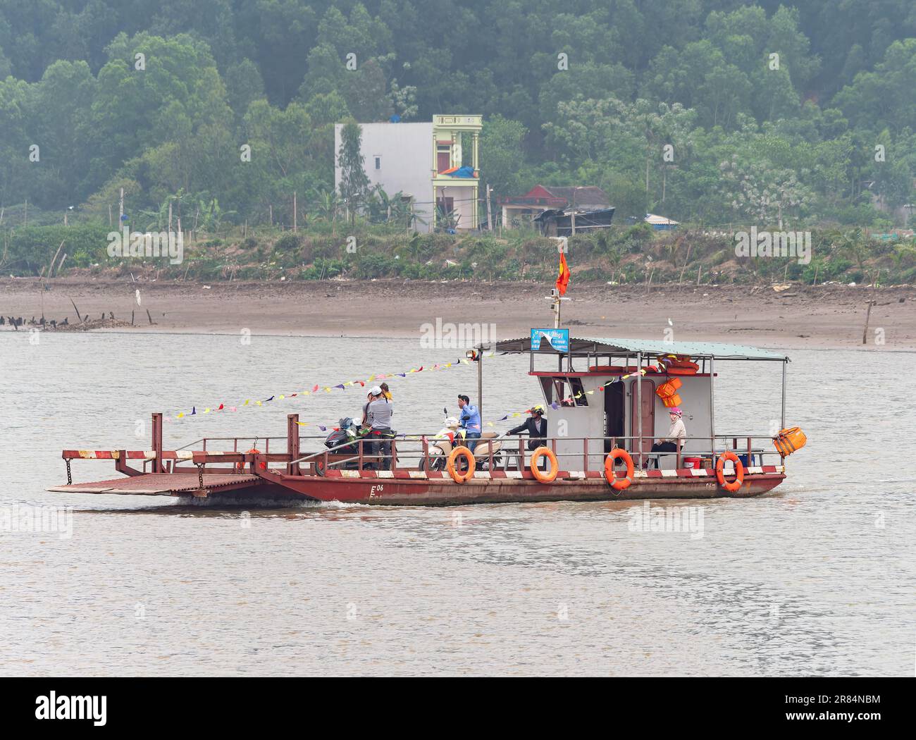 Simple car ferry traversant une rivière dans la province de Thanh Hoa au Vietnam avec des passagers et quelques motos à bord. Banque D'Images