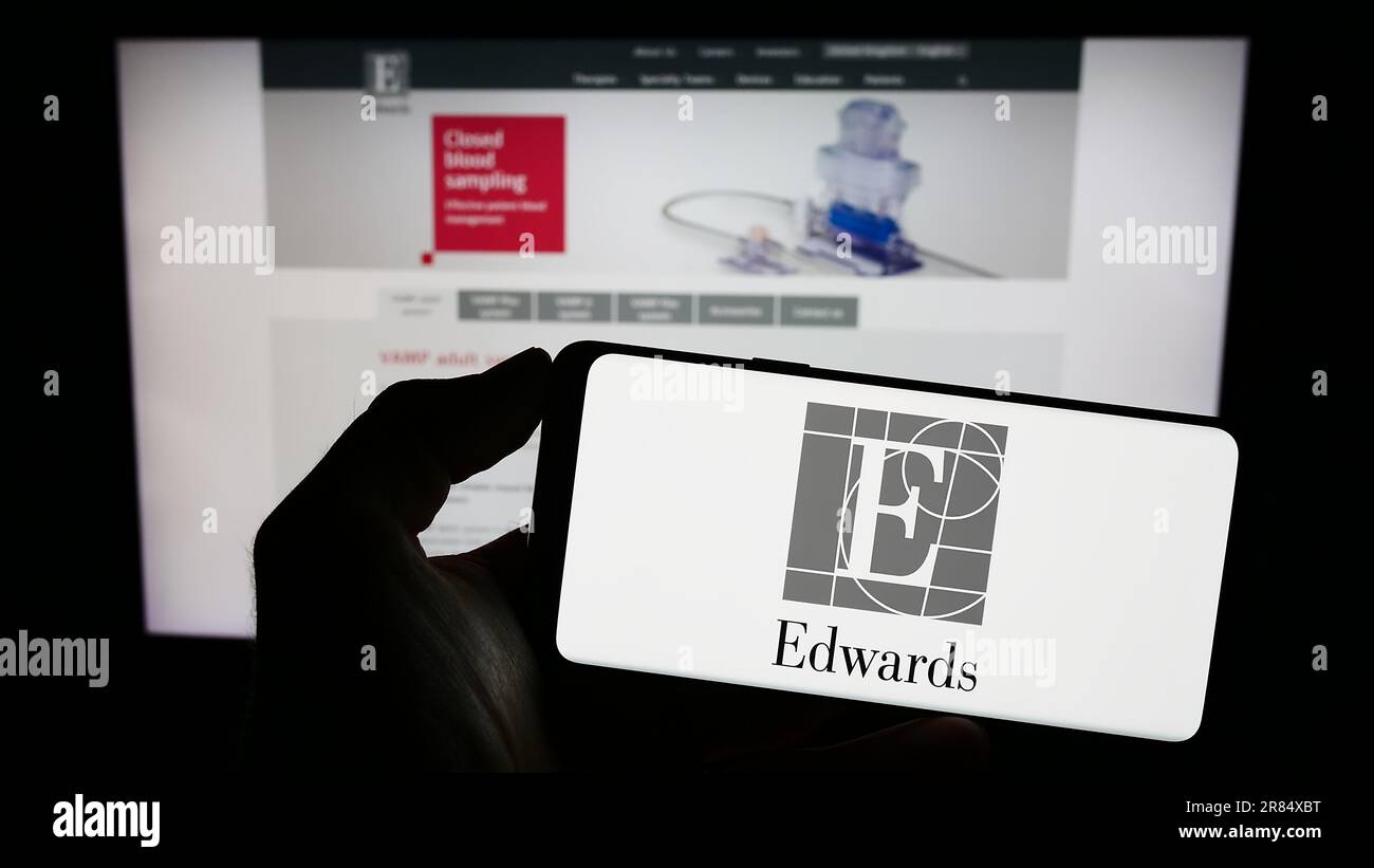 Personne tenant un téléphone portable avec le logo de la société américaine Edwards Lifesciences Corporation sur l'écran devant la page Web d'affaires. Mise au point sur l'affichage du téléphone. Banque D'Images