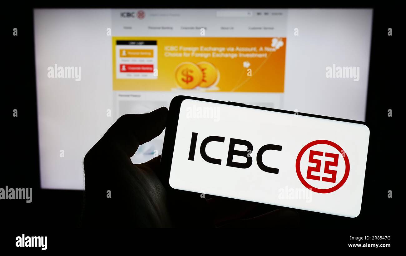Personne tenant un téléphone portable avec le logo de la société chinoise de services financiers ICBC à l'écran en face de la page Web d'affaires. Mise au point sur l'affichage du téléphone. Banque D'Images