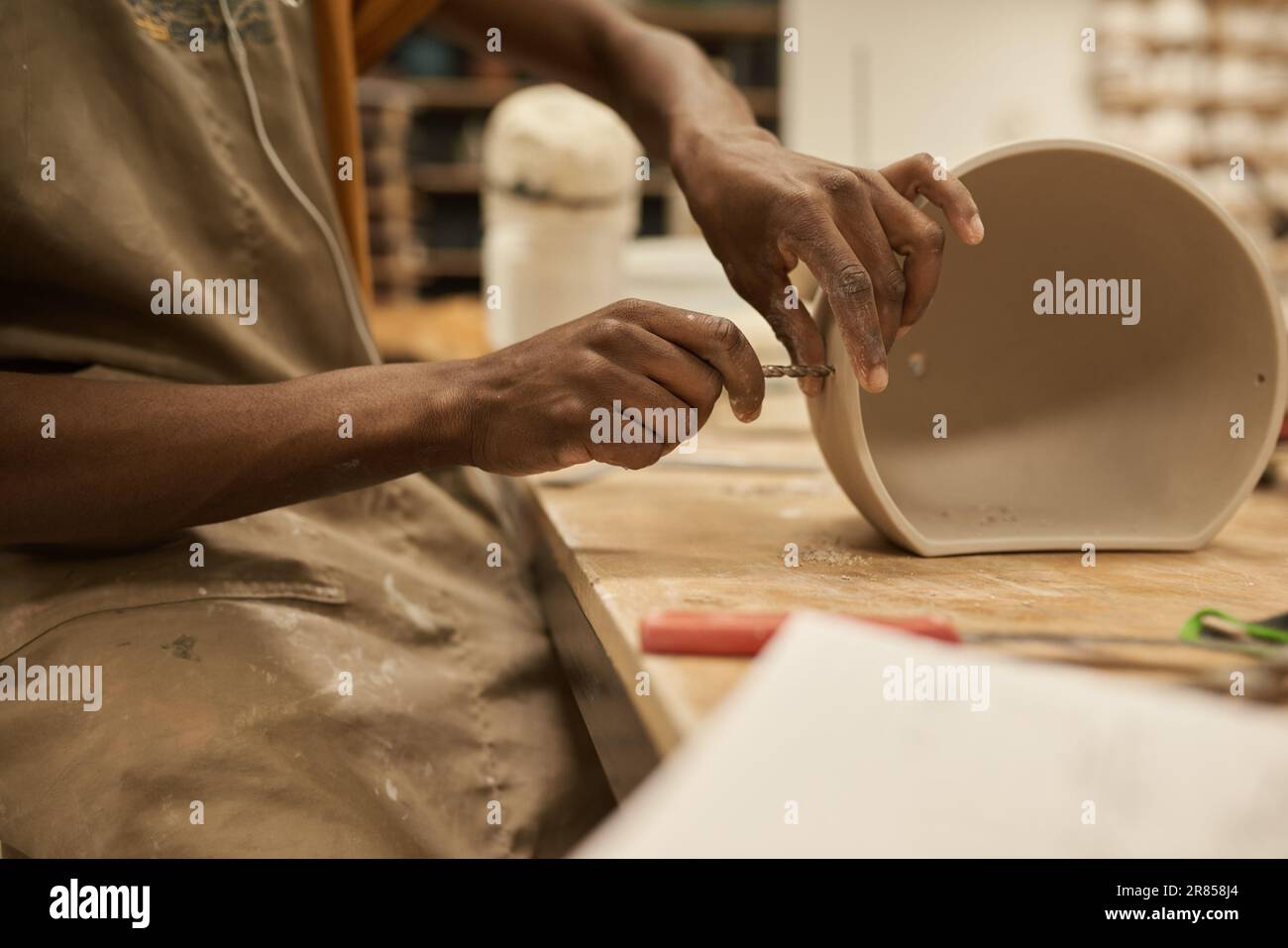 Céramiste africain faisant des trous dans un pot à un établi dans un studio Banque D'Images