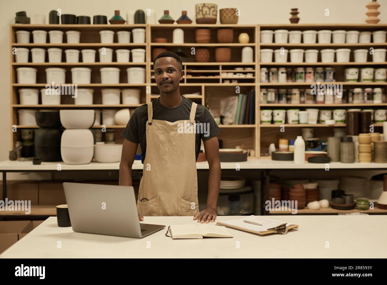 Jeune directeur de studio de céramique africain debout à une table dans un atelier Banque D'Images