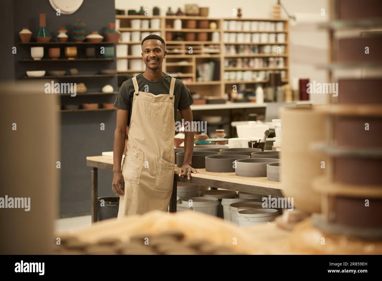 Jeune potier africain souriant travaillant dans un grand atelier de céramique Banque D'Images