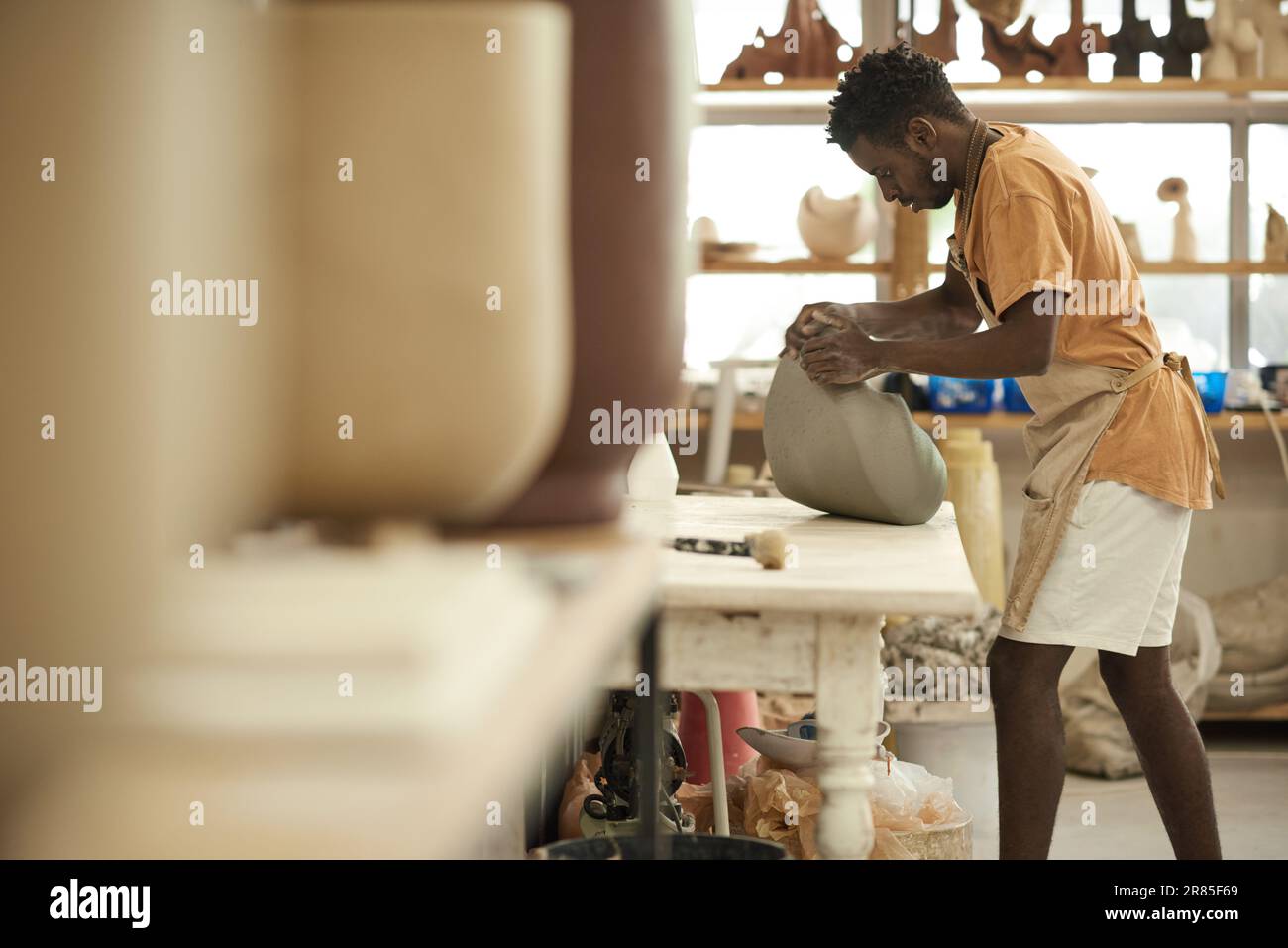 Céramiste africain moulant un morceau d'argile dans un atelier de poterie Banque D'Images