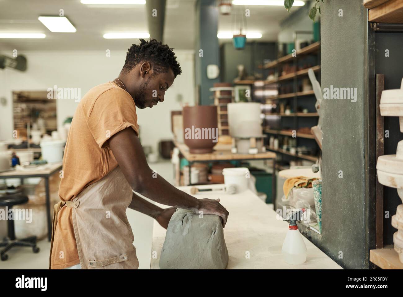 Jeune potier africain travaillant avec une grande dalle d'argile humide à un établi Banque D'Images