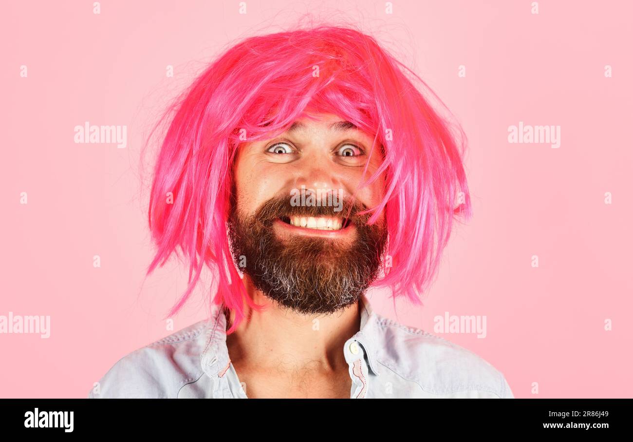Drôle d'homme barbu dans perruque rose. Homme souriant avec barbe et moustache dans une perruque colorée. Expression de face. Émotions. Hipster en periwig. Fête. Élégant Banque D'Images